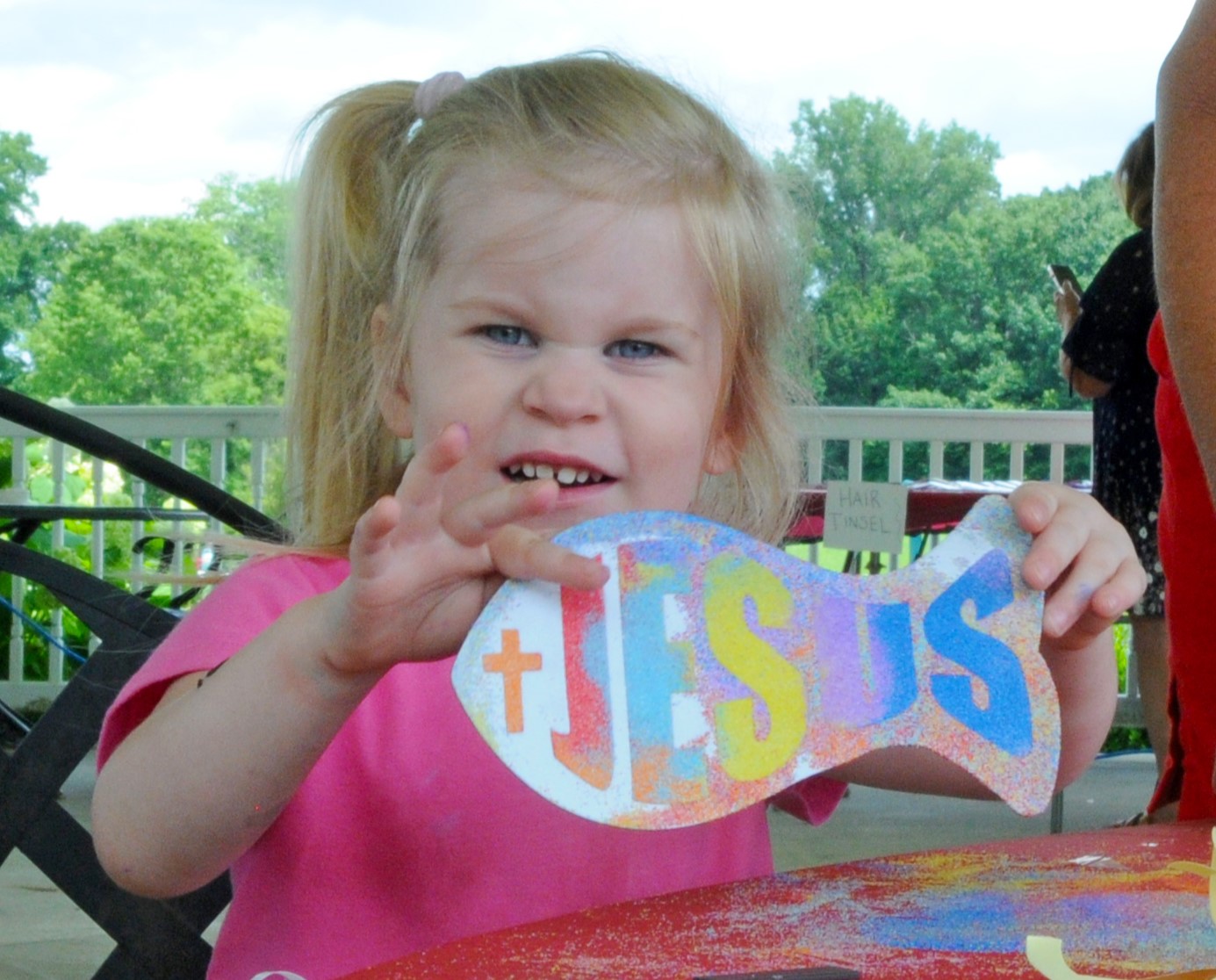 A little girl shows off a colorful Jesus fish painting craft at Concordia's Summer Festival